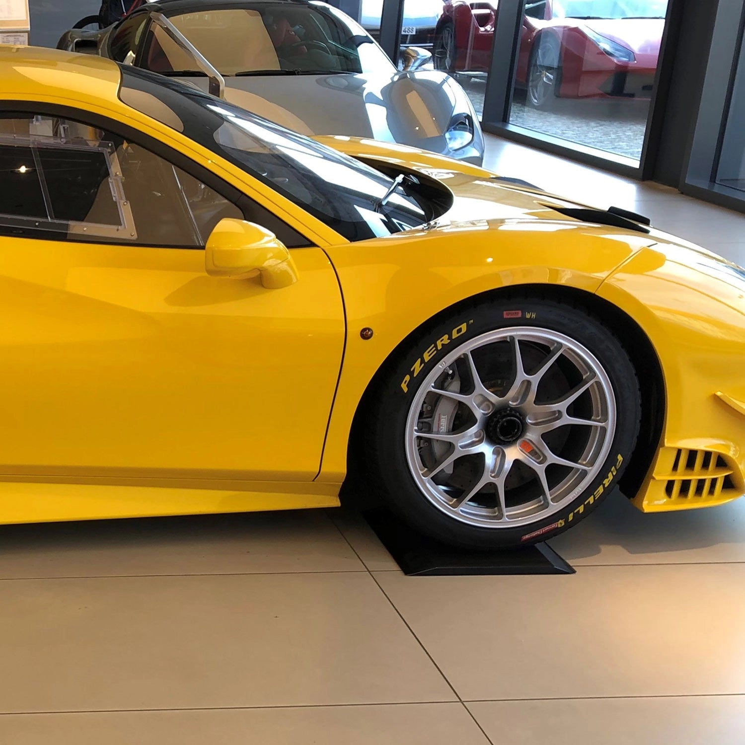 Gelbes Sportauto steht auf einem schwarzen Reifenschoner aus Pu-Gel.