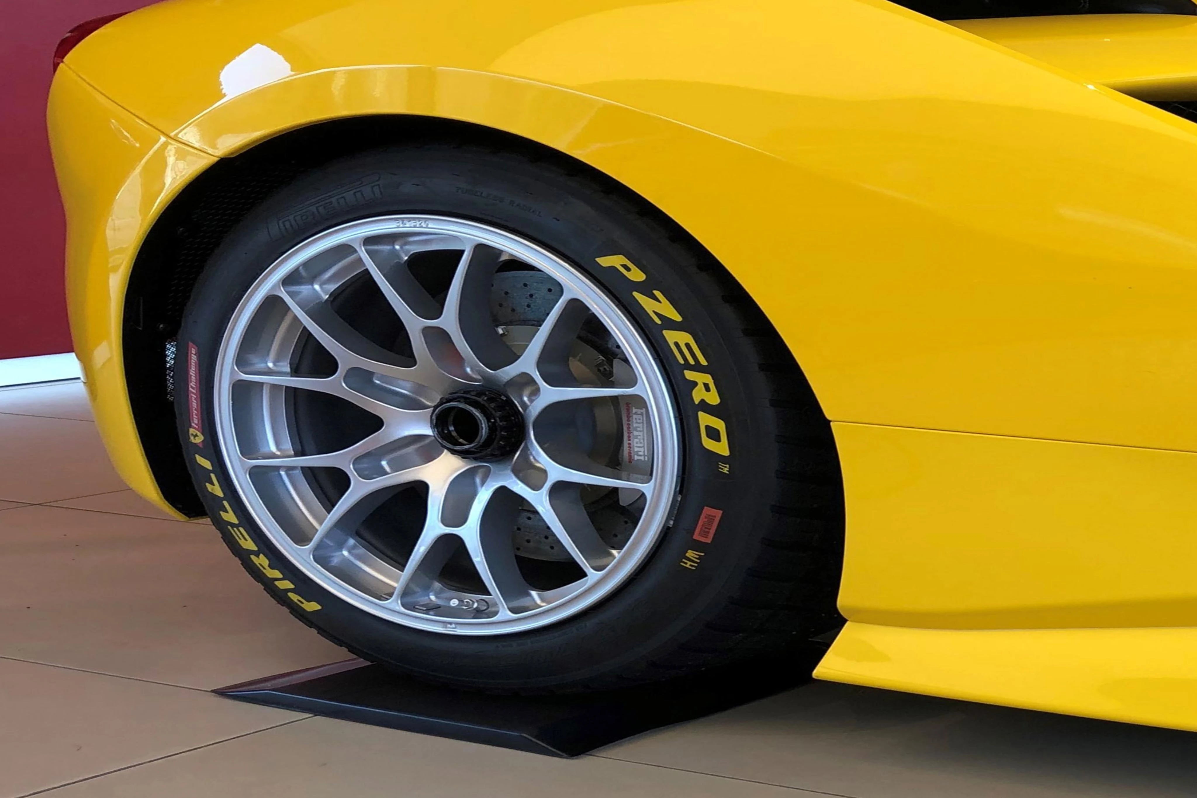 Gelber Ferrari steht mit einem reifen auf einem schwarzen Reifenschoner aus dem patentierten Flexigel®.