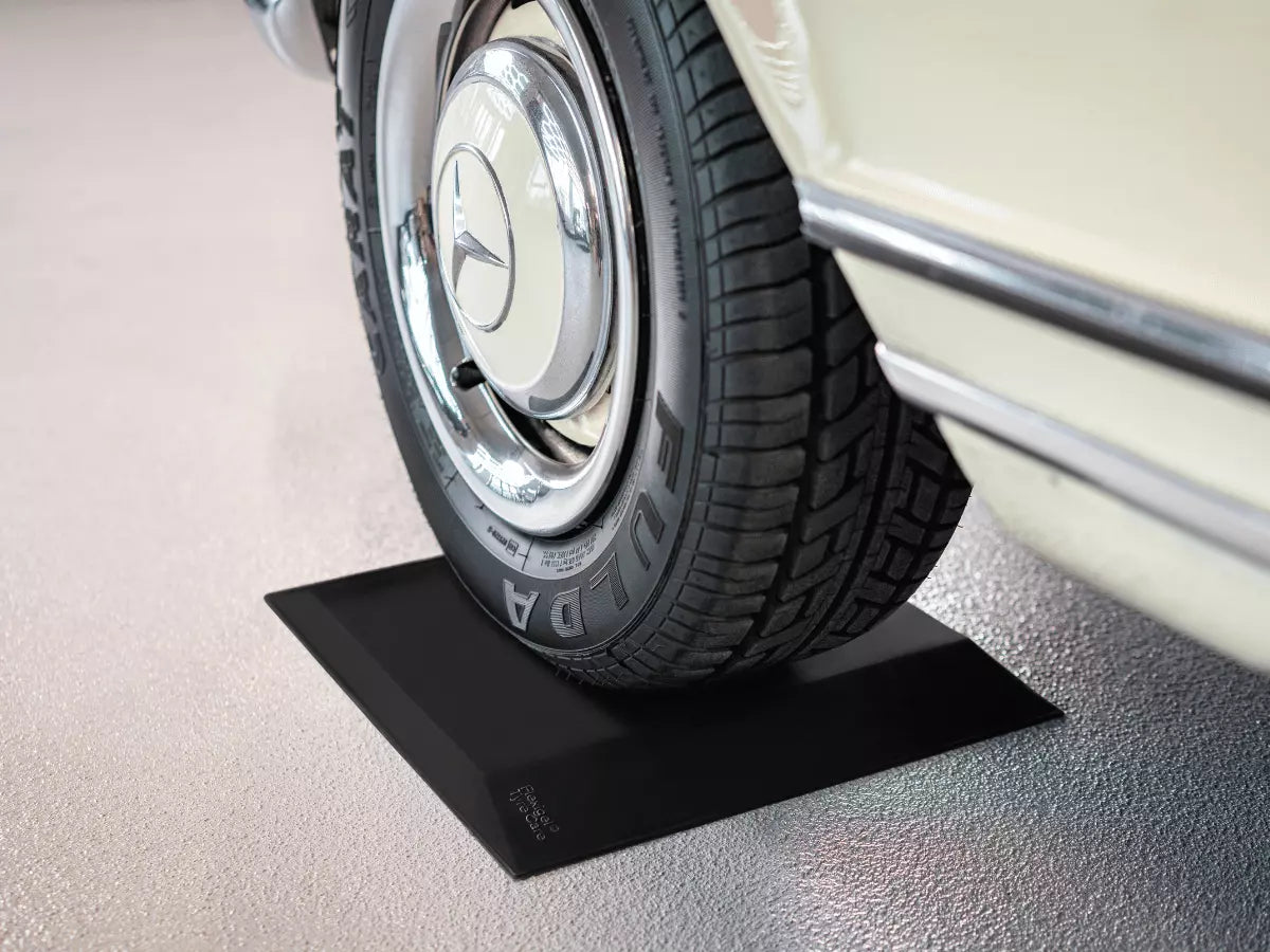 Ein weißer Oldtimer steht mit einem Reifen auf einem schwarzen Flexigel® Tyre Care Reifenschoner