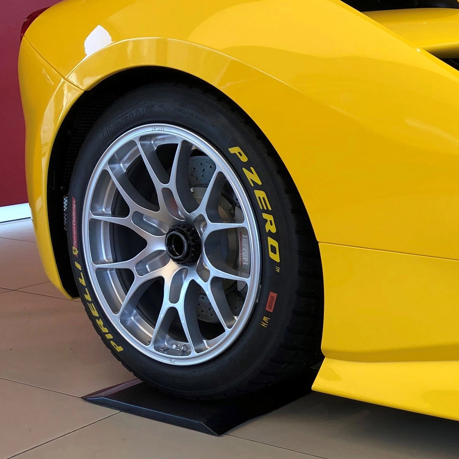 Gelber Ferrari steht mit einem Reifen auf einem Flexigel® Reifenschoner.